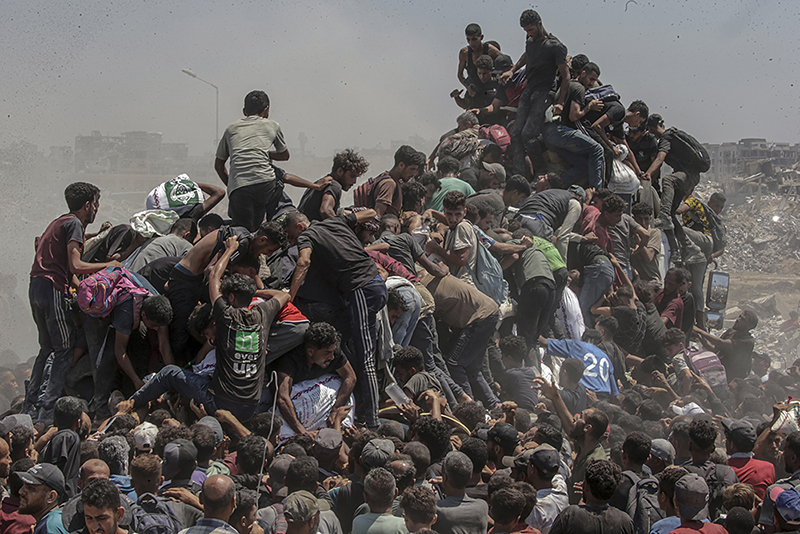 Title: Aid Emergency in Gaza Credit: &copy; Saber Nuraldin, EPA ImagesCaption: Palestinians climb onto an aid truck as it enters the Gaza Strip via the Zikim Crossing in an attempt to get flour, during what the Israeli military called a &ldquo;tactical suspension&rdquo; in operations to allow humanitarian aid through. 27 July 2025.Story: In 2025, famine took hold amid what an independent UN Human Rights Commission inquiry has concluded is a genocide in Gaza. Israel disputes this. Israeli authorities imposed a complete aid blockade in March, a tactic described by humanitarian organizations as the weaponization of starvation. When international pressure led to a partial reopening of crossings in May, most deliveries went through the Gaza Humanitarian Foundation (GHF), established by the US and Israel to bypass the UN-led aid system. Its operation, which put military personnel in charge, was widely condemned by global human rights and legal organizations as unethical and in violation of international law. The UN reports that between late May and early October, at least 2,435 Palestinians were killed seeking food at or near GHF collection points. The GHF shut down when a fragile ceasefire went into effect in October. Despite some aid entering Gaza, more than 75% of the population still faced hunger and malnutrition in December. The photographer was born in Gaza and has documented life there since 1997.